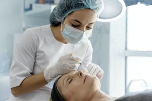 Senior woman attending beautician, having anti-aging injection at her face