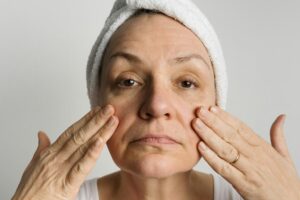 Middle-aged woman lookin in a mirror and checking bags under the eyes, skin and wrinkles. Skincare